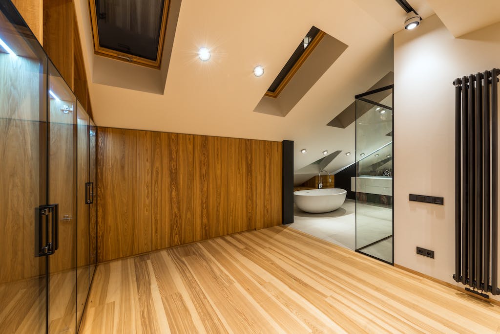 Creative design of bathroom with bath on floor under windows illuminated by lamps in house